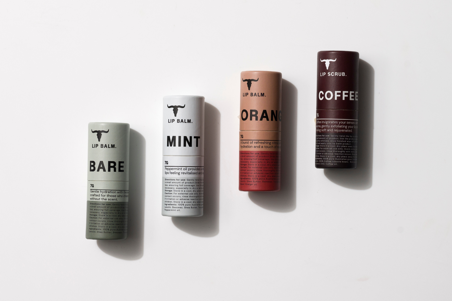 Four cylindrical tubes on a white surface labeled BARE, MINT, ORANGE, and COFFEE, each representing different lip balm or lip scrub flavors, arranged side by side vertically.