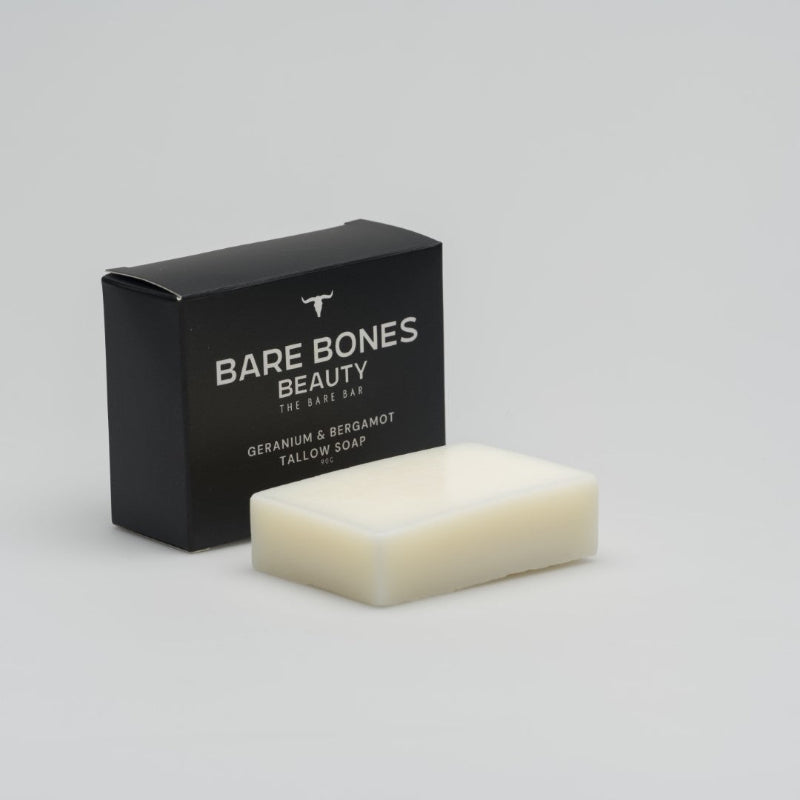 A rectangular white tallow soap rests before a black box labeled "Bare Bones Beauty Australia, The BARE bar – Tallow Soap," featuring geranium & bergamot for a moisturizing cleanse, set against a plain light background.