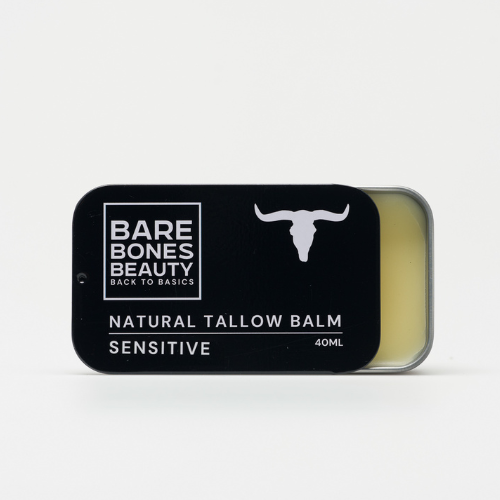 A rectangular tin of Bare Bones Beauty Australia Sensitive Tallow Balm 40mL for sensitive skin, with a black lid featuring a white cow skull logo and text, sits partially open to show the hydrating yellow balm inside.