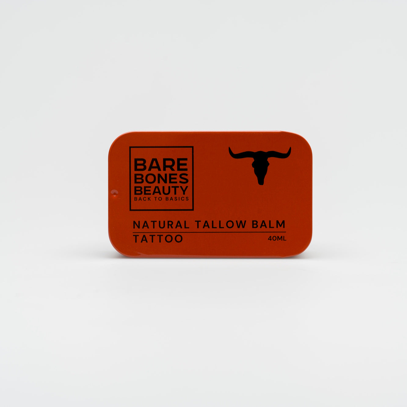 A rectangular red tin of Bare Bones Beauty Australia Tattoo Balm, featuring a black bull’s head on the right, sits on a white background—ideal for skin repair with natural ingredients.