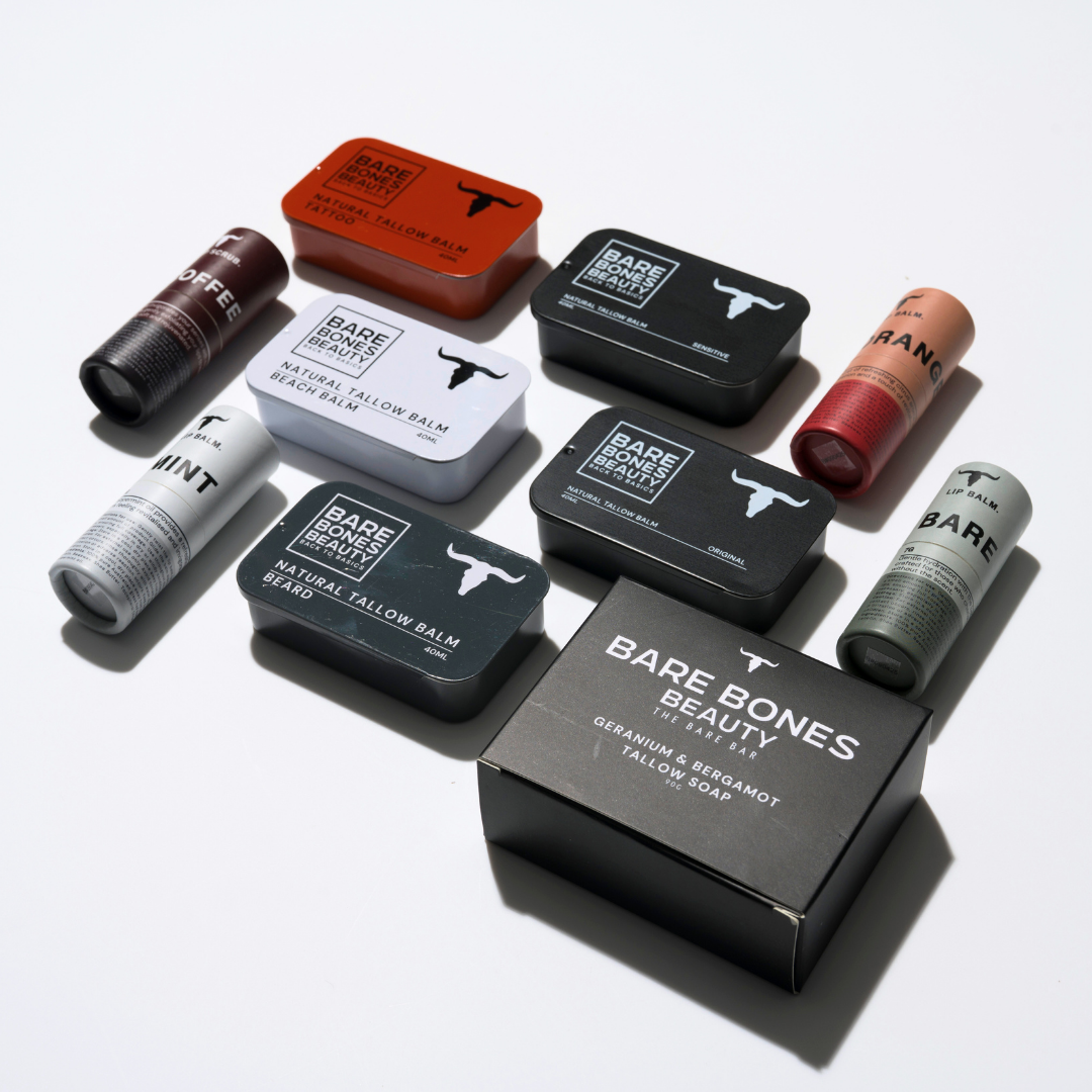 The EVERY SINGLE BONE – Bundle by Bare Bones Beauty Australia features lip and tallow balms in tins and tubes with black, white, red, and green packaging, arranged neatly in a grid on a white surface.